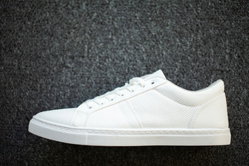 Pair of new stylish white sneakers on floor at home