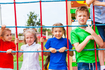 Friends on climbing net looking at camera