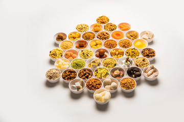 Rangoli of sweets and Farsan/snacks in bowls for Diwali with diya over white background