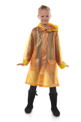 Full shot of a little blonde girl dressed in an orange nacre raincoat, black jeans, black top and black high shammy boots. The raincoat with pockets is buttoned with press-studs, 