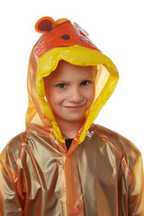 Medium close-up shot of a little girl dressed in an orange nacre raincoat buttoned with press-studs. The hood with child cartoon picture and wrists of the raincoat are fringed with orange elements. 