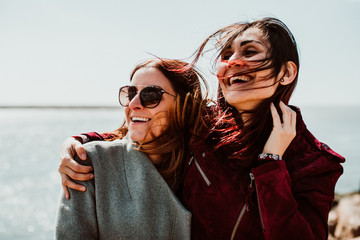 .Lesbian couple laughing together on their trip to Porto in Portugal. Walking along the coast on a windy afternoon. Inclusive love. Lifestyle. Travel photography