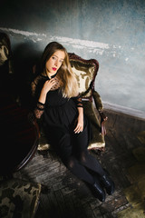 a girl sits in a vintage chair and looks up