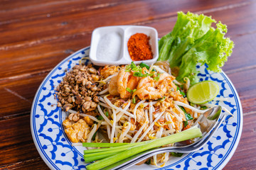 Fried Rice Sticks with Shrimp or Pad Thai Goong Sod with sugar and chilli powder in beautiful dish on wooden table, special Thai food in Thailand