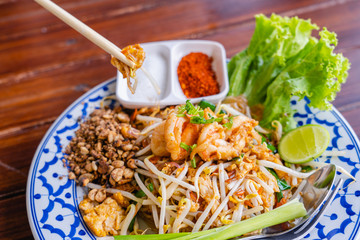 Fried Rice Sticks with Shrimp or Pad Thai Goong Sod with sugar and chilli powder in beautiful dish on wooden table, special Thai food in Thailand