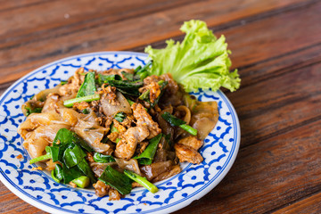 Fried Noodle in Soy Sauce in beautiful dish on wooden table, special Thai food in Thailand