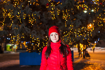 Attractive woman in red coat under city Christmas tree