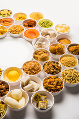 Rangoli of sweets and Farsan/snacks in bowls for Diwali with diya over white background