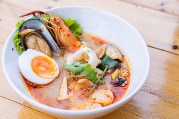 Traditional Thai food spicy soup with shrimp or tom yum seafood noodle in bow on wooden table with copy space.