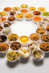 Rangoli of sweets and Farsan/snacks in bowls for Diwali with diya over white background