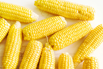 Fresh corn on the cob on white wooden surface, top view