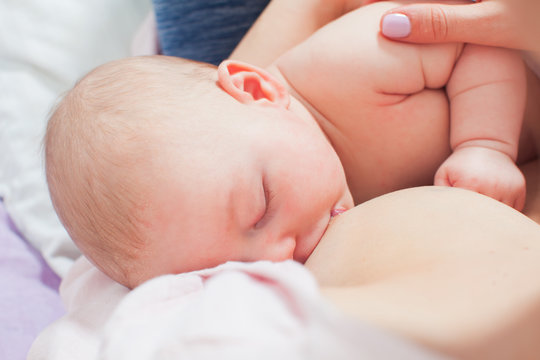 Sleeping baby while breastfeeding in mothers arms