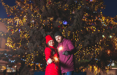 Outdoor portrait of young couple lighting sparkles