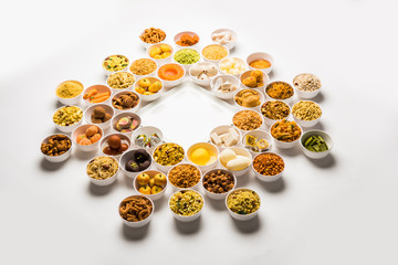 Rangoli of sweets and Farsan/snacks in bowls for Diwali with diya over white background