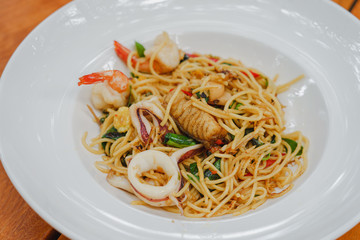 Homemade Spaghetti spicy seafood with prawn and squid on white dish.