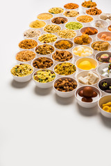 Rangoli of sweets and Farsan/snacks in bowls for Diwali with diya over white background