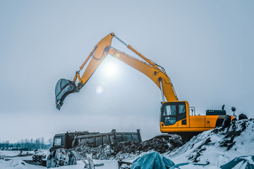 Excavator is loading excavation to the truck. Excavators are heavy construction equipment consisting of a boom, dipper or stick , bucket and cab on a rotating platform.