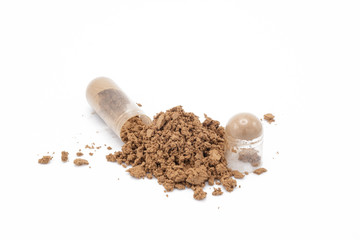 Capsule of medicine and the powder that has been poured out on white background