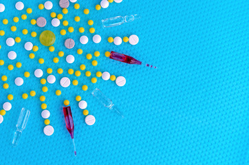 Ampoules for injection, pills and vitamins on a blue background. Medical concept.