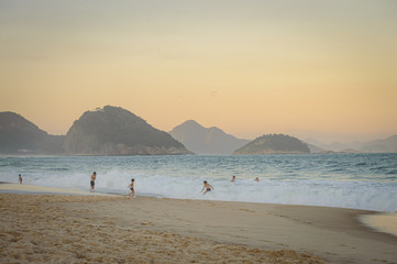 Fototapeta na wymiar Playa en Copacabana con morros y gente en el mar