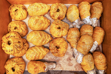fresh pastries and a variety of buns in assortment on the counter in a wooden box in the bakery shop