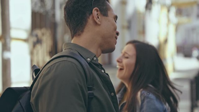 interracial couple laughing and kissing on street