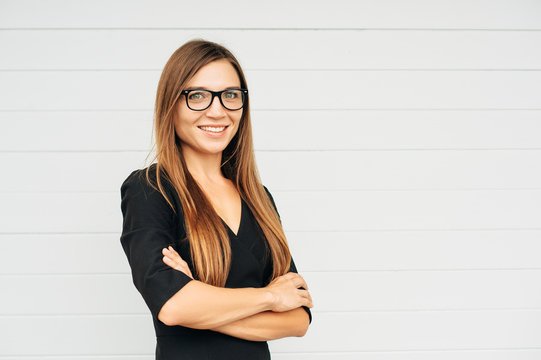 Close up portrait of beautiful young businesswoman wearing eyeglasses, arms crossed