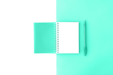 Top view of opened trendy mint cover spiral notepad with pen on mint and white background. Mockup for your design. Flat lay.