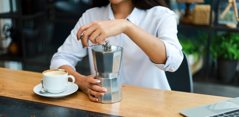 Obraz na płótnie Canvas Asian woman drinking coffee with coffee grinder in cafe