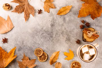 Top view composition with vintage styled cup of coffee with marshmallows and autumn themed decoration, fallen leaves on textured background. Top view, flat lay, copy space.