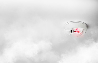 close-up of smoke alarm or smoke detector in home going off with thick smoke