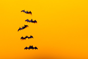 Witch on broom and black paper bats flying on yellow background. Halloween concept. Paper cut style. Top view