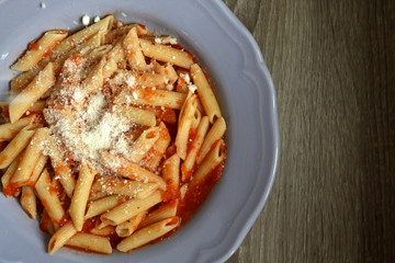 Plate of pasta with homemade tomato sauce. Sprinkling parmesan cheese on top. Flat lay.