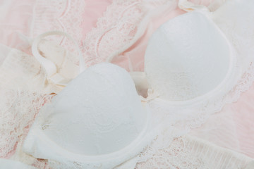 Fototapeta na wymiar White women underwear with lace on pink background. whitebra and pantie.Copy space. Beauty, fashion blogger concept. Romantic lingerie for Valentine's day temptation. Erotic concept.