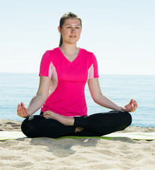 Fototapeta na wymiar Woman exercising yoga poses on beach