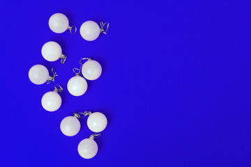 Minimal New Year greeting card with white glass balls on blue colored background. Christmas flat lay border with copy space. Top view.