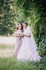 Obraz na płótnie Canvas Bride and bridesmaid with a bouquet