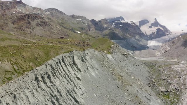Aerial shot overflying Findelgletscher glacier moraine on a partly cloudy day. Zermatt, Switzerland