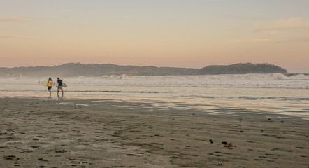 Fototapeta na wymiar Surfers at sunset on the beach
