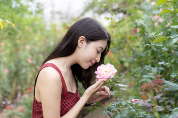 Fototapeta premium Woman in a red dress posing in a rose garden.
