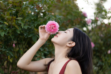 Naklejka premium Woman in a red dress posing in a rose garden.