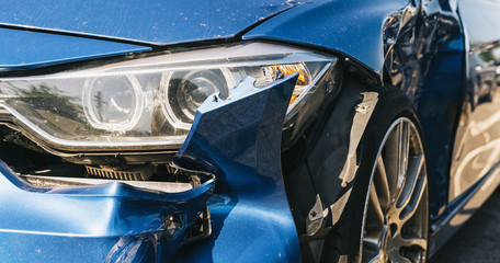 Car crash or accident. Front fender from a blue car and light damage and scratchs on bumper. Broken vehicle detail or close up. 