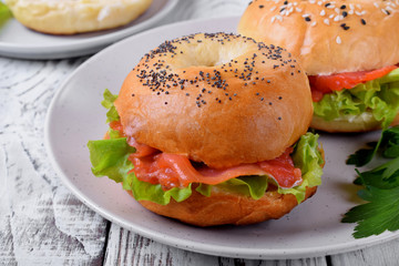 Bagel sandwich with smoked salmon and lettuce salad on ceramic plate