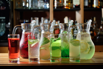 Different soft drinks in transparent jugs on a dark wooden background. menu for catering