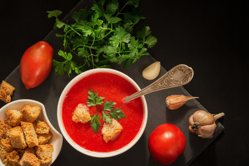 Tomato soup with garlic, crackers and parsley on a wooden table close-up. horizontal top view.
