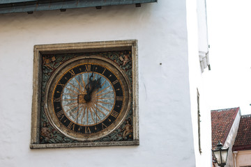 Ancient outdoor clock on white wall in old Tallinn, Estonia