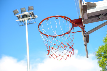 bright blue sky with basketball hoop and spotlight