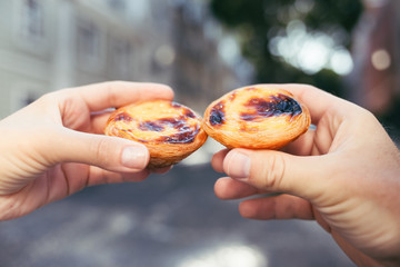 Traditional portuguese desserts in woman's and man's hands. Pastel de Nata.