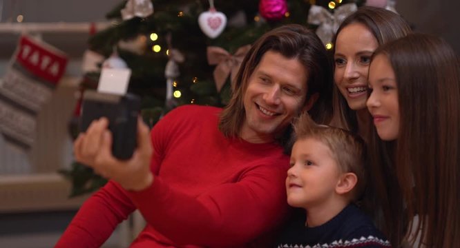 Beautiful family celebrating Christmas at home and taking instant pictures