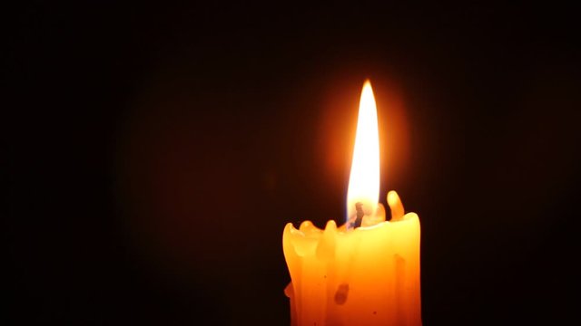 Closeup of candle flame on black. Old white candle